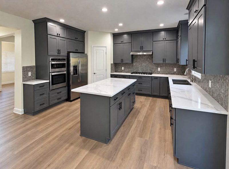 Remodeled kitchen with grey shaker cabinets, a large island, quartz countertops and luxury vinyl plank flooring